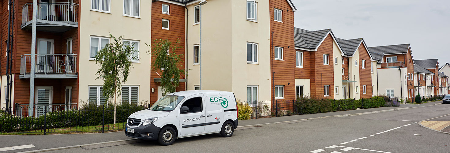 ECS van with branding throughout in the foreground of a high rise residential estate