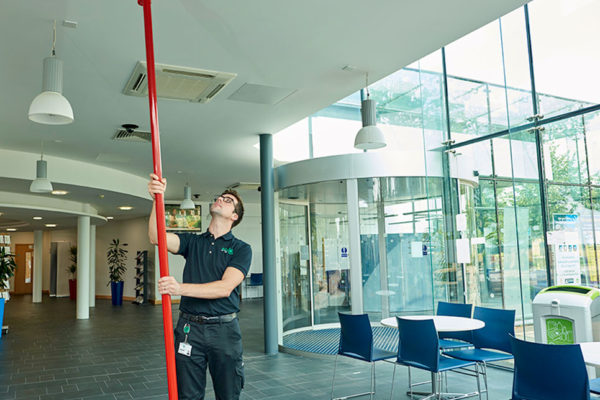 Electrician using long pole to reach fire alarm high up